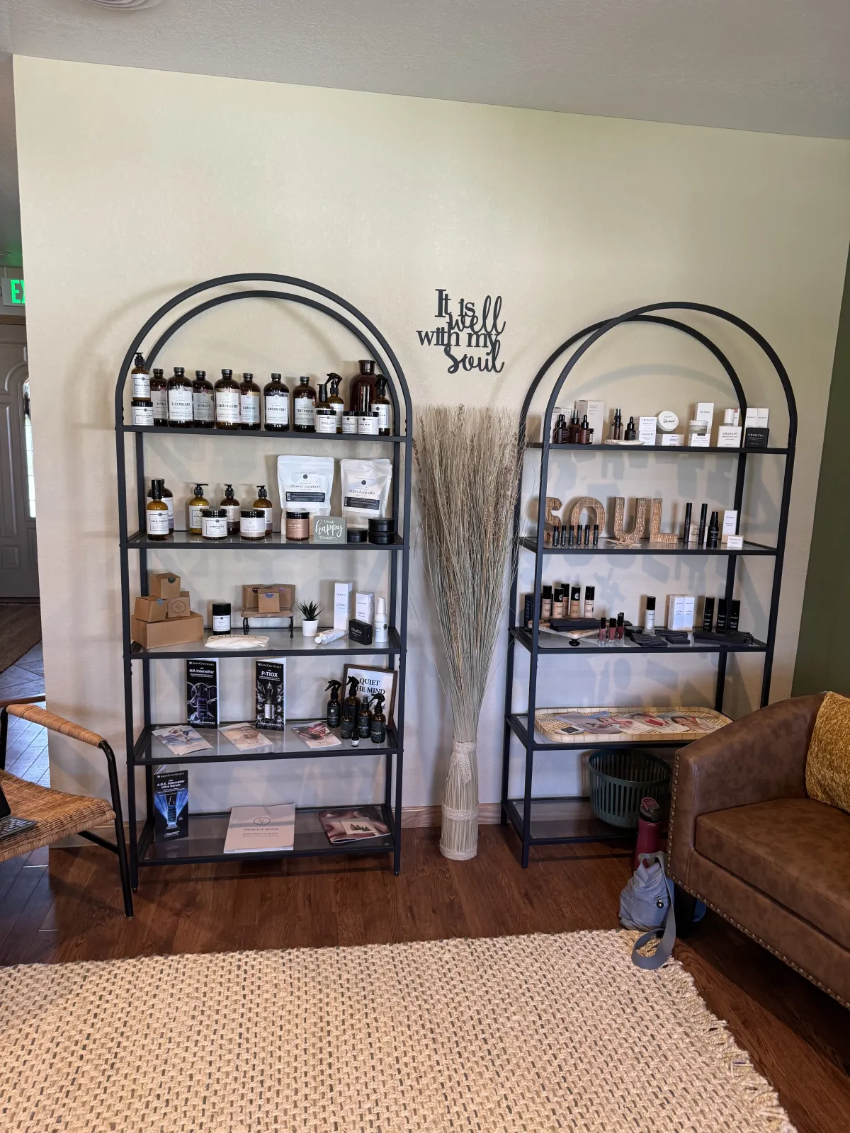 Arched shelves stocked with professional skincare products beside a sign reading It is well with my soul